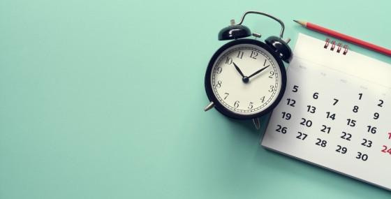 Alarm clock next to small paper calendar